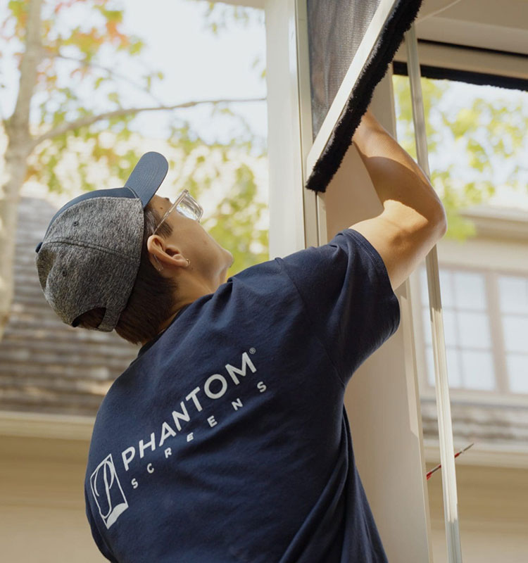 A Phantom Screens technician installing outdoor screens on a porch