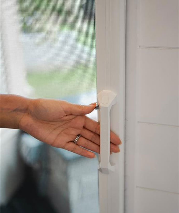Hand operating the quick-release thumb latch on a retractable screen door handle.