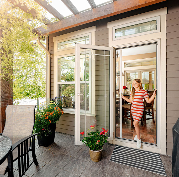 Girl stepping through a patio doorway with a retractable screen pulled across behind her.